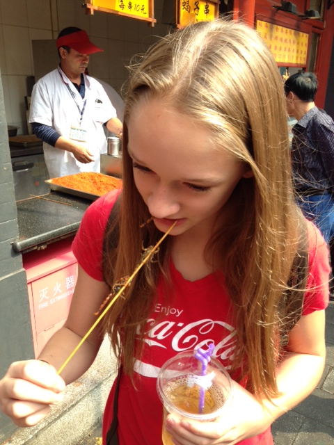 Ally taking a bite of scorpion skewer.