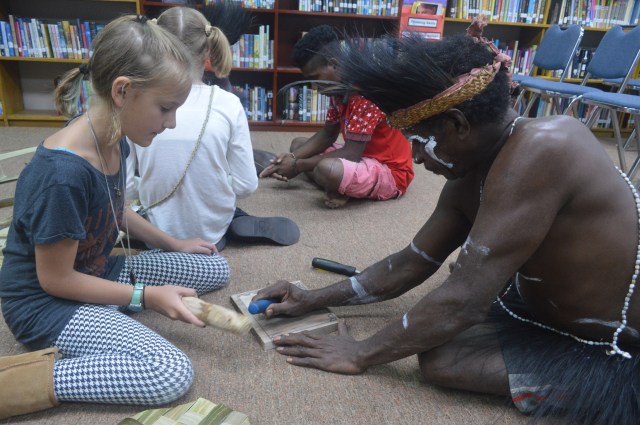 A Komoro tribesman teaching Kylee how to carve wood. Kylee carved a casssowary (a large, mean, flightless bird native to Papua) on her board.