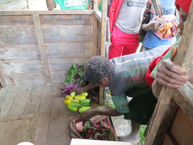 A Moni woman setting out lettuce and cucumbers for us to look at and buy.