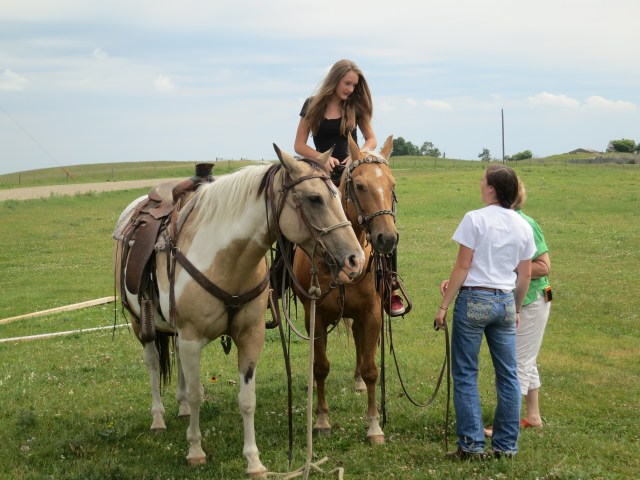 Ally getting on her horse, with the help of kari's daughter,